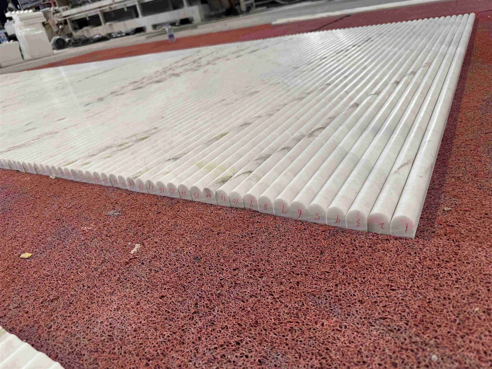 Factory dry layout of numbered long Dione Spider Marble fluted tiles, showing the rounded profiles, honed surfaces, and coordinated natural veining before export packing. Factory dry layout of numbered long Dione Spider Marble fluted tiles, showing the rounded profiles, honed surfaces, and coordinated natural veining before export packing.